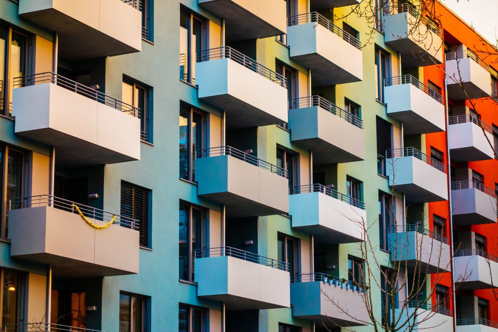 Apartments with several stories, rectangle beige balconies, and orange, green, yellow, and red paint.

