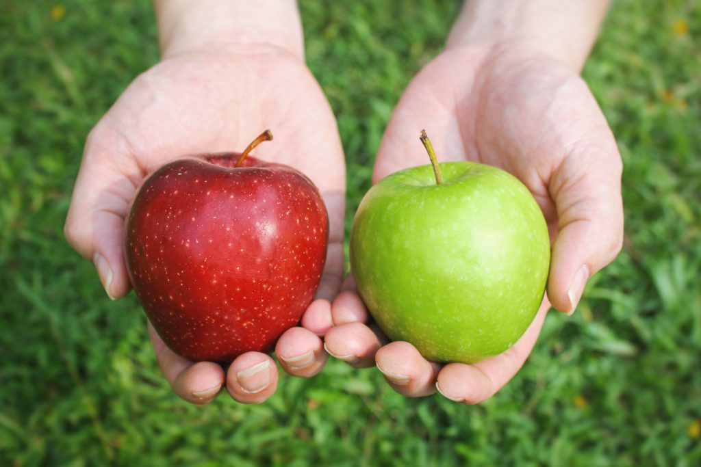A red and a green apple held in two hands.