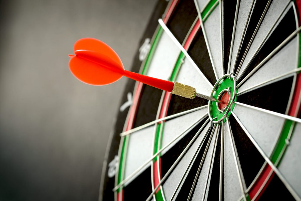 A red dart and a bulls eye on a target.